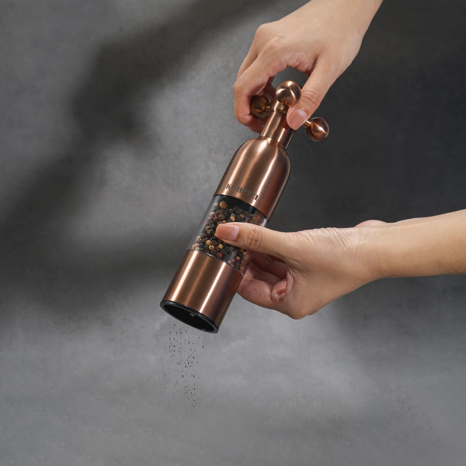 Kraftel copper salt and pepper grinder in use over food, adjustable ceramic burr mill